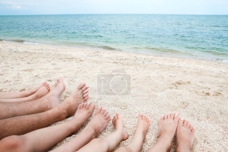 Téléchargez les photos : Jambes de la belle famille entière sur le sable près du fond de la mer - en image libre de droit