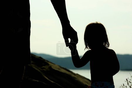 Photo for Happy parent with child in nature by the sea silhouette - Royalty Free Image