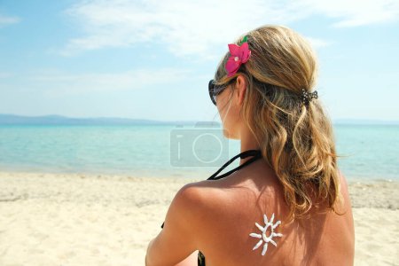 Photo for Happy girl on the sea with a picture of the sun on her back - Royalty Free Image