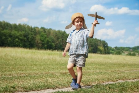 Téléchargez les photos : Bébé garçon par l'avion joue sur la nature dans le parc. Garçon en vacances pilote. - en image libre de droit