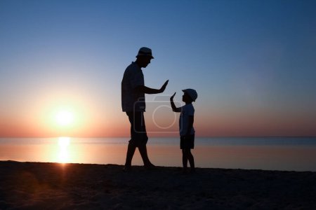 Photo for Happy parent with child by the sea play on nature silhouette travel - Royalty Free Image