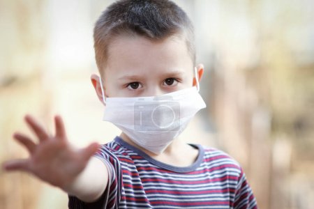 Téléchargez les photos : Coronavirus and air pollution PM2.5 concept. Petit garçon européen portant un masque pour protéger pm2.5 et montre un geste d'arrêt de la main pour arrêter l'épidémie du virus de la couronne. Symptômes massifs du coronavirus et du virus épidémique
. - en image libre de droit