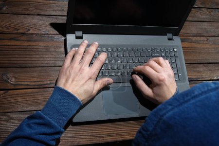 Téléchargez les photos : Hacker avec ordinateur portable se trouve à une table et le code binaire abstrait. Programmes virtuels de menace de vie professionnelle. - en image libre de droit