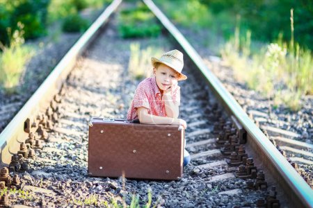 Téléchargez les photos : Garçon cow-boy avec valise et chemin de fer Western Travel Concept - en image libre de droit
