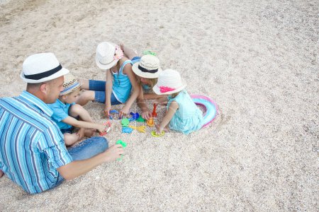 Téléchargez les photos : Joyeux famille jouant au bord de la mer sur le fond de sable - en image libre de droit