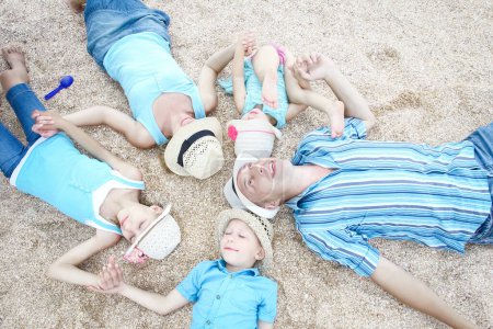 Foto de Familia feliz jugando junto a la orilla del mar en el fondo de la arena - Imagen libre de derechos
