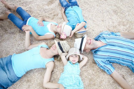 Foto de Familia feliz jugando junto a la orilla del mar en el fondo de la arena - Imagen libre de derechos