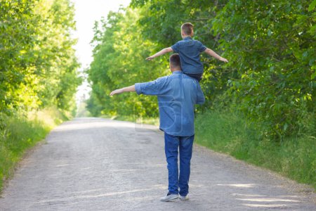 Foto de Happy child on the shoulders of a parent in nature on the way to travel - Imagen libre de derechos