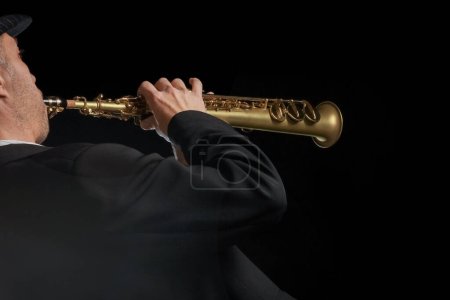 Photo for Soprano saxophone in the hands of a guy on a black background - Royalty Free Image