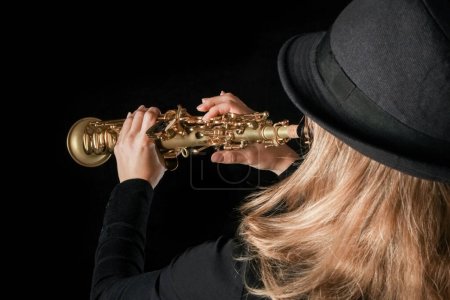 Téléchargez les photos : Saxophone soprano dans les mains d'une fille sur fond noir - en image libre de droit