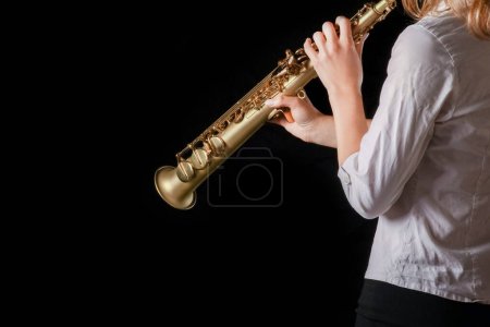 Photo for Soprano saxophone in the hands of a girl on a black background - Royalty Free Image