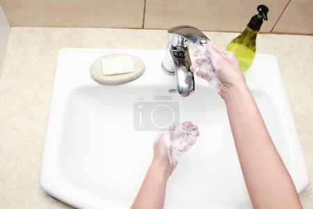 Téléchargez les photos : Les mains avec du savon sont lavées sous le robinet avec de l'eau. Nettoyer de l'infection et la saleté et le virus. À la maison ou au bureau d'ablution de l'hôpital. - en image libre de droit