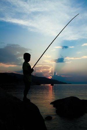 Téléchargez les photos : Pêche enfant heureux par la silhouette de la mer - en image libre de droit