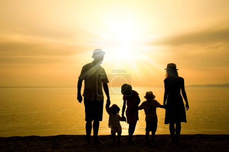 Téléchargez les photos : Famille heureuse dans la nature en bord de mer sur une silhouette de voyage - en image libre de droit