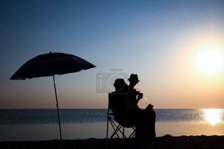 Téléchargez les photos : Joyeux couple au bord de la mer au coucher du soleil sur silhouette de voyage dans la nature - en image libre de droit