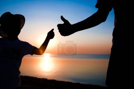 Téléchargez les photos : Mains de heureux père et enfant au bord de la mer sur la nature silhouette Voyage - en image libre de droit