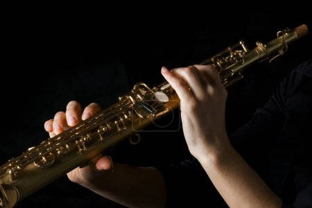 Photo for Soprano saxophone in hands on a black background - Royalty Free Image