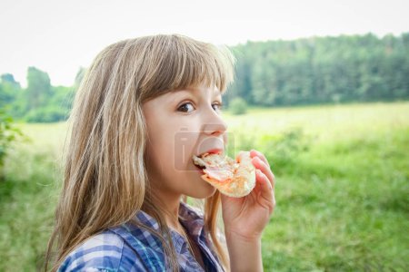 Téléchargez les photos : Enfant manger une pizza savoureuse sur la nature de l'herbe dans le parc - en image libre de droit