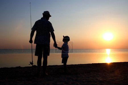 Téléchargez les photos : Père heureux et les enfants pêcheurs pêchent des poissons par la mer sur la silhouette de la nature Voyage - en image libre de droit