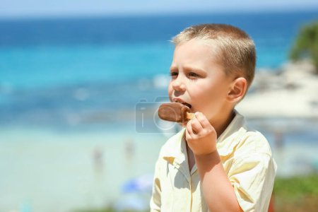 Téléchargez les photos : Heureux enfant garçon avec de la crème glacée au bord de la mer dans la nature dans le voyage du parc - en image libre de droit