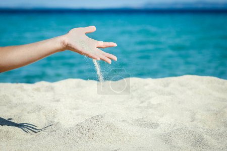 Foto de Manos vertiendo arena cerca de la orilla del mar en viaje de fin de semana naturaleza - Imagen libre de derechos