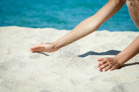 manos vertiendo arena cerca de la orilla del mar en viaje de fin de semana naturaleza