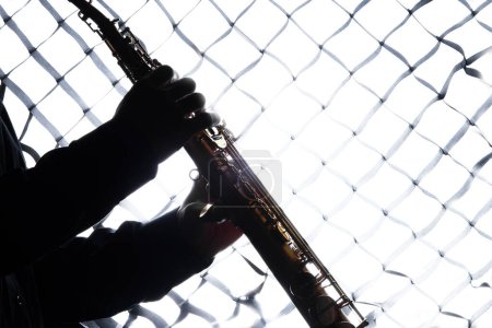 Photo for Saxafon on a white background in the hands of a musician silhouette - Royalty Free Image