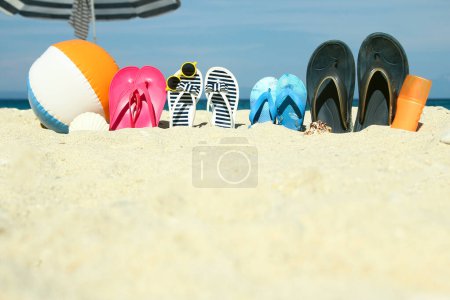 Photo for Beach summer holiday banner background. Flip-flops and hat with a board and ball on the sand near the ocean. Summer accessories on the seashore. Tropical vacation and relax travel concept. Top view and copy space. - Royalty Free Image
