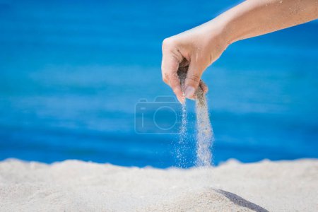 Foto de Las manos derraman arena del mar sobre la naturaleza en un viaje. Vacaciones en el mar pasa el tiempo de arena. - Imagen libre de derechos