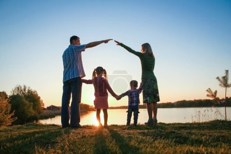 Téléchargez les photos : Famille silhouette, y compris son père, sa mère et deux enfants entre les mains de - en image libre de droit