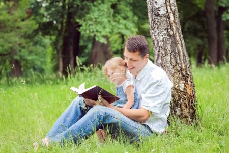 Photo for Happy parents with a child read the Bible in the nature park - Royalty Free Image