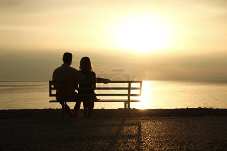 Photo for Happy couple on a bench by the sea on nature in travel silhouette - Royalty Free Image