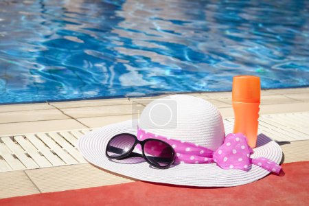 Photo for Beautiful hat near the pool with cream and glasses background - Royalty Free Image