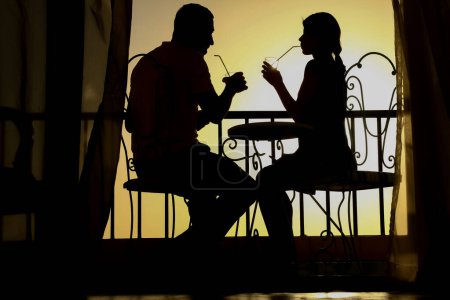 Foto de Pareja silueta de hombre y mujer en un balcón junto al mar en el fondo. Reunión en una cita doble en la terraza. - Imagen libre de derechos