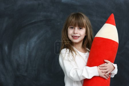 Photo for Little girl student with a big pencil on black background - Royalty Free Image
