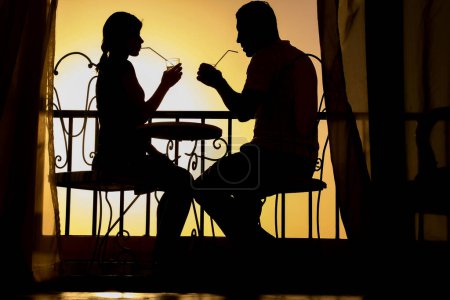 Foto de Pareja silueta de hombre y mujer en un balcón junto al mar en el fondo. Reunión en una cita doble en la terraza. - Imagen libre de derechos