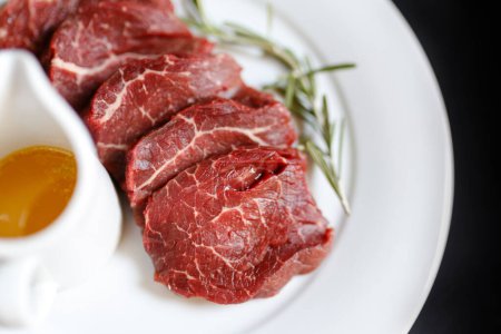 Photo for Veal raw steaks served on a plate with olive oil and herbs - Royalty Free Image