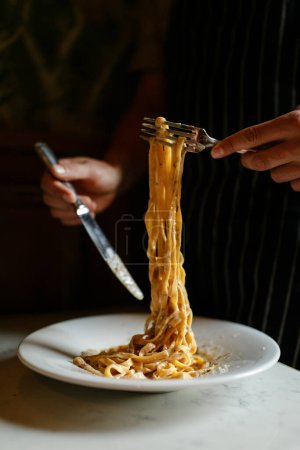 Foto de Manos de hombre mezclando y comiendo pasta en el restaurante - Imagen libre de derechos