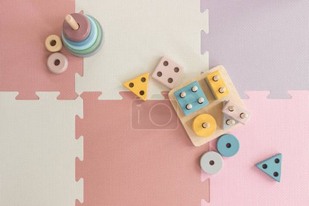 Foto de Juguetes de madera de apilamiento de colores en la alfombra de juego rosa en la habitación del vivero - Imagen libre de derechos