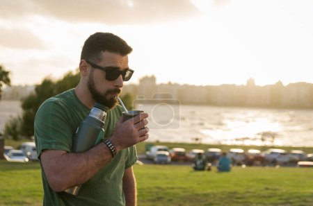 Mann trinkt Chimarrao, Mate (eine Infusion von Yerba Mate mit heißem Wasser) bei Sonnenuntergang in Uruguay
