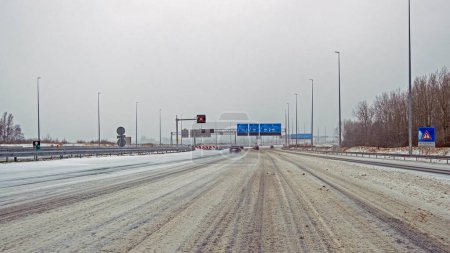 Photo for Driving in a snowstorm on the highway A9 near Amsterdam in the Netherlands in winter - Royalty Free Image