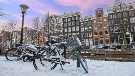 Téléchargez les photos : Ville enneigée Amsterdam aux Pays-Bas en hiver au coucher du soleil - en image libre de droit