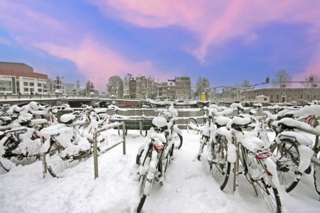 Téléchargez les photos : Ville enneigée Amsterdam aux Pays-Bas en hiver au coucher du soleil - en image libre de droit