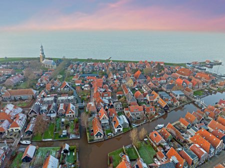 Téléchargez les photos : Aérien du petit village traditionnel enneigé Hindeloopen à l'IJsselmeer au coucher du soleil aux Pays-Bas - en image libre de droit