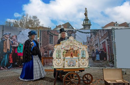 Téléchargez les photos : Deventer, Pays-Bas - 16 décembre 2023 : Un beau couple vêtu de vêtements de style victorien à l'orgue du tonneau lors du festival Dickens Plus de 950 personnages des célèbres livres de Charles Dickens revivent à Deventer, Pays-Bas - en image libre de droit