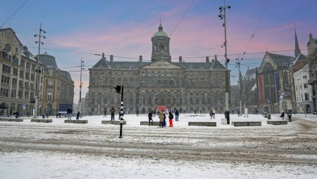 Téléchargez les photos : Ville enneigée Amsterdam sur la place du barrage aux Pays-Bas en hiver - en image libre de droit