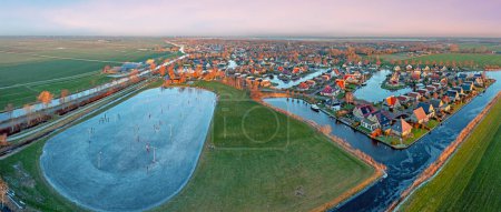 Photo for Aerial view on the traditional village Koudum with the ice rink in Friesland the Netherlands at sunset in winter - Royalty Free Image