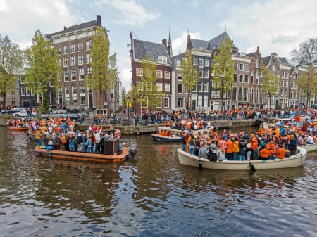 Photo for Amsterdam, Netherlands - April 27, 2024: Local dutch people celebrating kingsday on the canals in Amsterdam in the Netherlands - Royalty Free Image