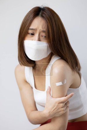 Concept image of fully vaccinated asian woman wearing face mask with side effect from vaccine shot or long covid