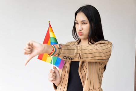 Téléchargez les photos : Personne LGBT non binaire montrant un mauvais rejet pouce vers le bas signe de la main, image concept pour le mois de la fierté de la sensibilisation LGBT - en image libre de droit